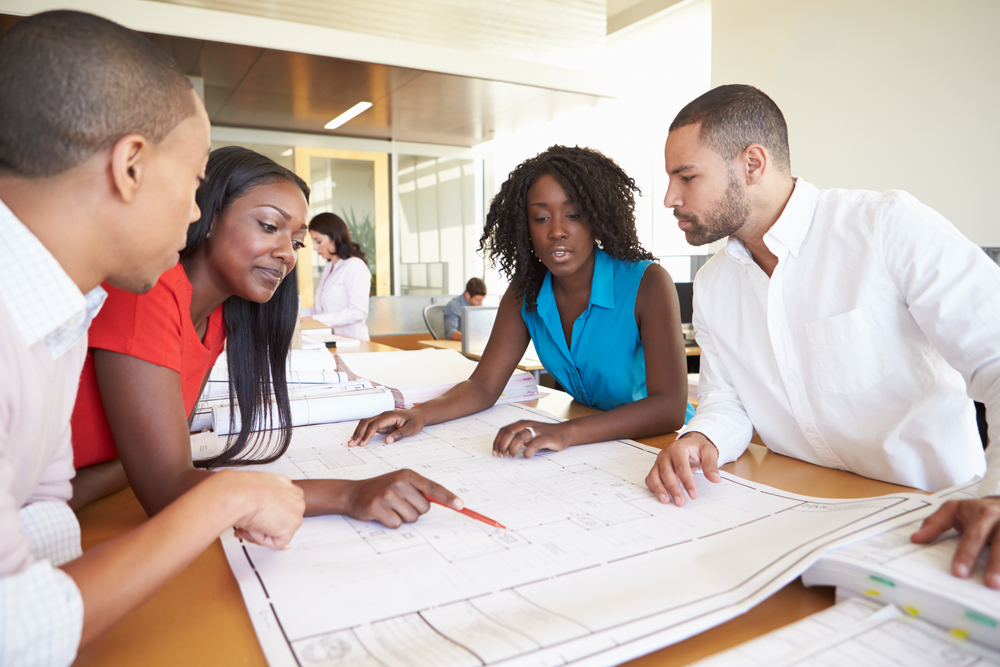 Diverse group of young professionals gathered around a table discussing project plans.